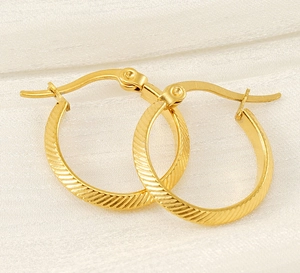 Detailed view of gold hoop earrings with diagonal texture and a hinged clasp closure