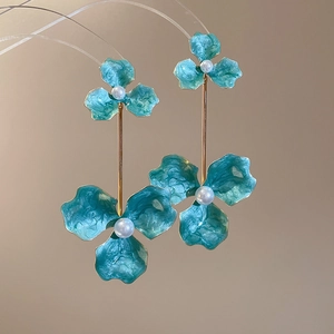 Close-up of sky blue enamel flower earrings with white pearl detail and gold stem