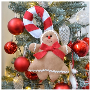Close-up of plush gingerbread man and candy cane hanging on a decorated Christmas tree