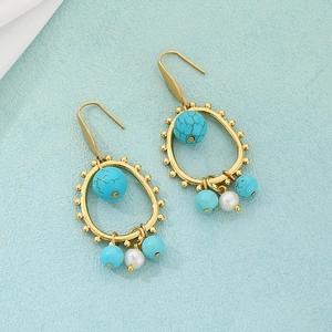 Detail of bohemian gold earrings with turquoise beads and pearls on blue background