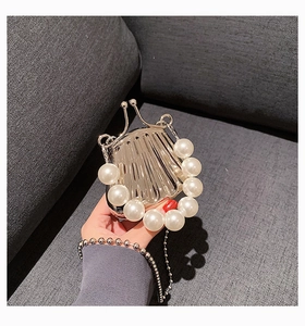 Makroaufnahme einer silbernen Mini-Muschel-Tasche mit großen Perlen und Metallkette