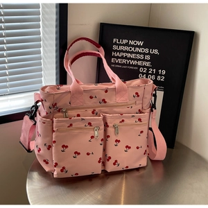 Detailed close-up of a pink cherry print tote bag with dual front pockets on a metal surface