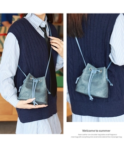 Detail view of blue leather drawstring bucket bag worn by model in natural light