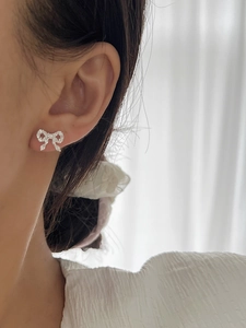 Close-up of sparkling bow-shaped earrings with micro-set zircons on model ear