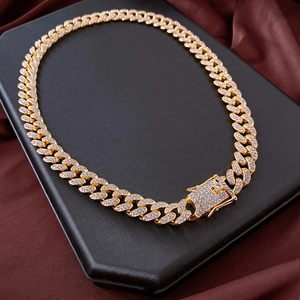 Close-up of gold iced-out Cuban link chain with sparkling rhinestones on a display tray