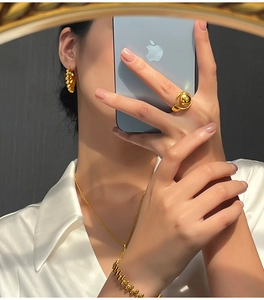 Close-up of a gold-plated geometric moon cutout ring set worn in a warm sunlight setting