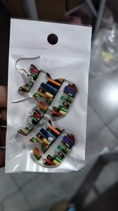Detail of acrylic cat earrings with colorful bookshelf pattern on a card