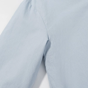 Close-up of light blue cotton linen shirt shoulder seam with fine stitching detail