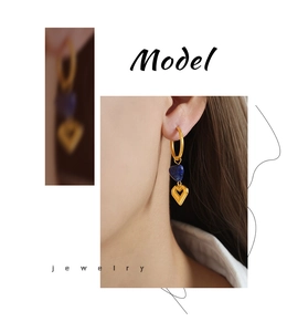 Detail of gold-plated earrings with deep blue heart stone and hollow heart pendant