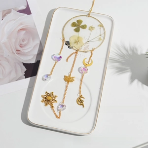 Detail of suncatcher with dried four-leaf clover, crystal beads and golden metal charms