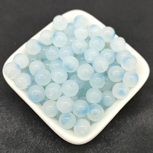 Macro view of 8mm translucent milky white beads with frosted blue speckles for DIY jewelry