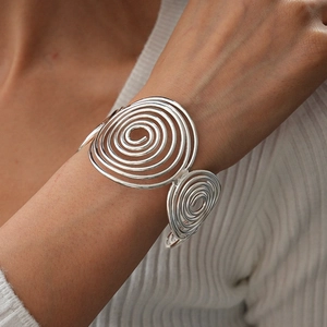 Macro detail of silver spiral geometric metal cuff bracelet on model wrist