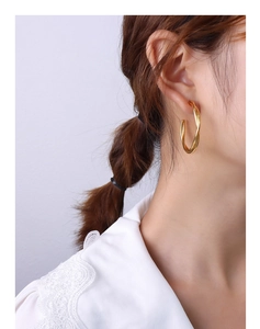 Close-up of a double-layered gold twisted hoop earring worn by a model in a professional style