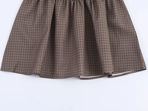 Detailed macro view of the brown and black plaid pleated skirt fabric with fine texture
