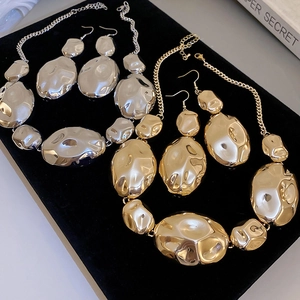 Detailed view of irregular molten texture gold and silver jewelry sets on black velvet