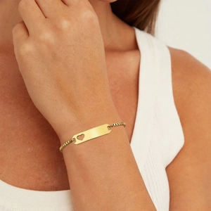 Detail of personalized gold rectangular bar bracelet with heart cutout on a wrist