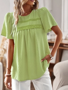 Detail of light green short sleeve top featuring lace splicing and textured jacquard fabric