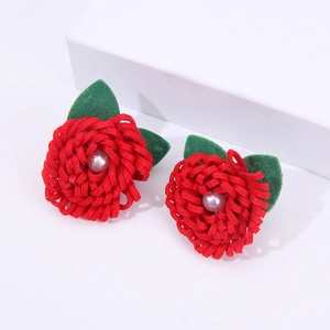 Nahaufnahme von handgemachten roten Stoffblumenohrringen mit grünen Filzblättern.