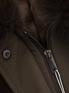 Detail of dark brown faux leather jacket with plush fur collar and metallic zipper texture