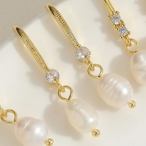 Macro view of gold freshwater pearl earrings with zircon stones and elegant metal bars