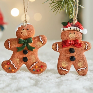 Resin gingerbread man ornaments hanging on a pine tree with festive snow background