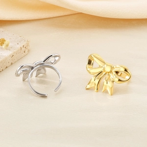 Macro view of adjustable bow rings in polished gold and silver finishes on a stone base