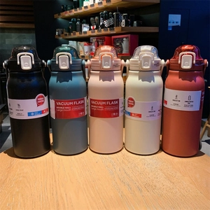 Detail of five assorted colorful stainless steel vacuum flasks with carry handles and lids