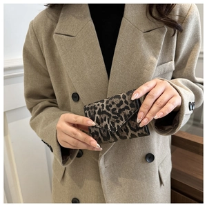 Primo piano del mini portafoglio leopardato tenuto da una modella in blazer beige