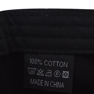 Detailed close-up of 100% cotton material label and wash care instructions on black cap