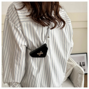 Détail d'un sac bandoulière noir avec fermoir papillon argenté et bandoulière chaîne