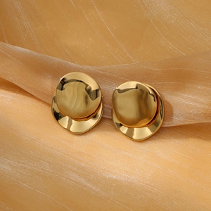 Polished gold drop earrings with wavy lotus design on a premium gold silk fabric background