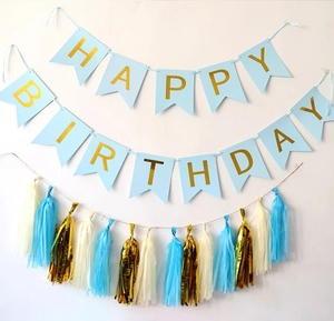 Detail of light blue Happy Birthday banner with gold foil letters and colorful tassels