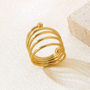Detail of multi-layer spiral gold ring with double beads on a stone and cream background