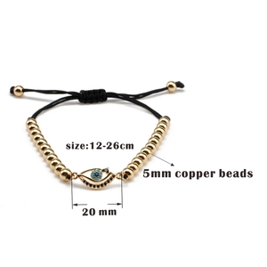 Détail des perles dorées de 5mm et du pendentif œil sur bracelet tissé ajustable