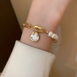 Close-up of a gold pearl bracelet featuring a crystal-encrusted smiley face pendant