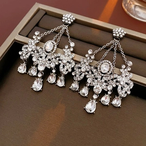 Detail view of silver drop earrings with floral rhinestones and hanging tassels