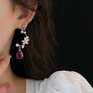 Detailed view of elegant gold floral earrings with crystal drop gems on a model