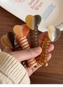 Macro shot of heart-shaped spiral hair coils in amber and beige held in hand