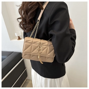 Detail of quilted beige chain shoulder bag with elegant gold S-buckle and tassel detail