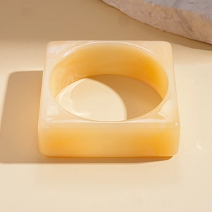 Macro view of geometric beige marble resin bangle with square and circular frame