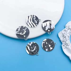 Macro view of five black and white enamel landscape charms on a white display tray