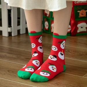 Festive red Christmas crew socks with snowman patterns and green accents on wood floor