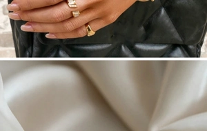 Detail of two 18K gold plated double-layer rings on hand and soft silk backdrop