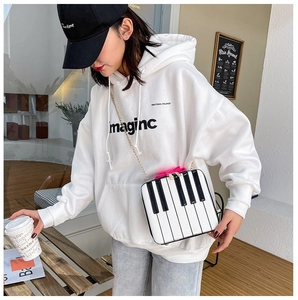 Detail of white mini piano crossbody bag with pink bow and musical keyboard pattern