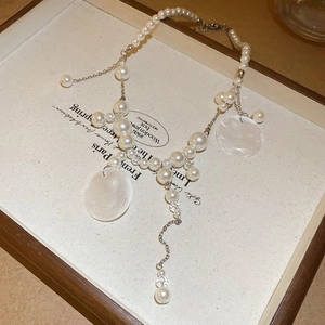 Detailed macro view of French vintage pearl necklace with shell tassels on display