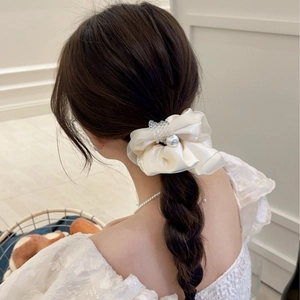Elegant cream satin scrunchie with crystal pearls shown on a braided hairstyle