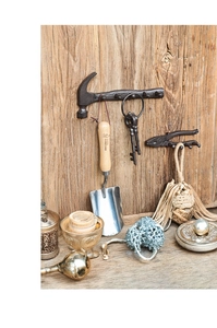 Detail view of retro cast iron hammer and plier hooks mounted on a rustic wood wall