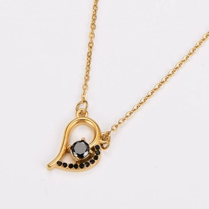 Macro shot of gold heart pendant with black zircon stones on a white background