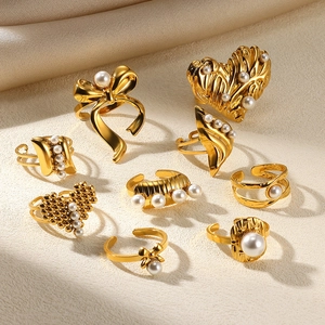 Elegant gold pearl ring set with bow and heart designs on beige textured fabric