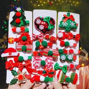 Main tenant un set de barrettes de Noël avec paillettes rouges, sapins et nœuds